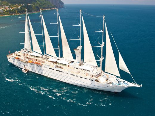Windstar Wind Surf sailing yacht under full sail along the coast